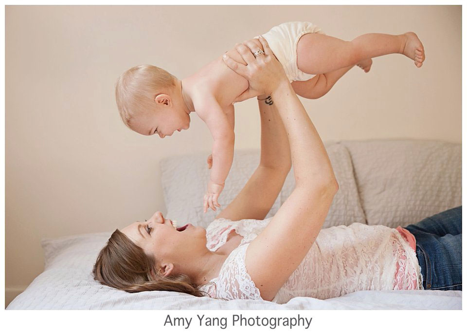 Mother lifting her smiling baby during a newborn photography in-home session in Charlottesville, VA.