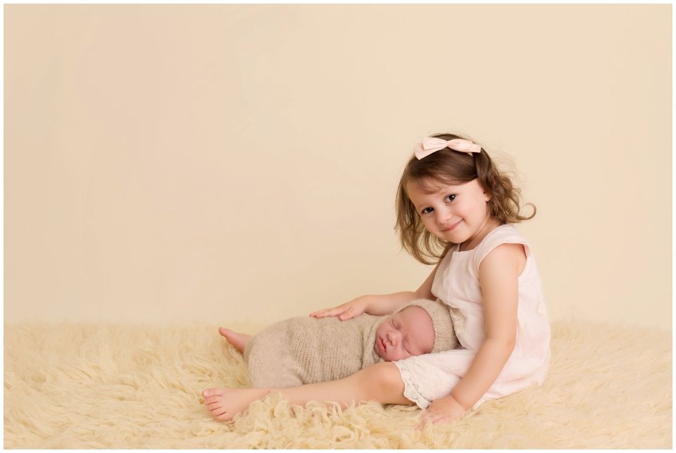 Smiling big sister holding her newborn baby for sibling newborn photos in Charlottesville.