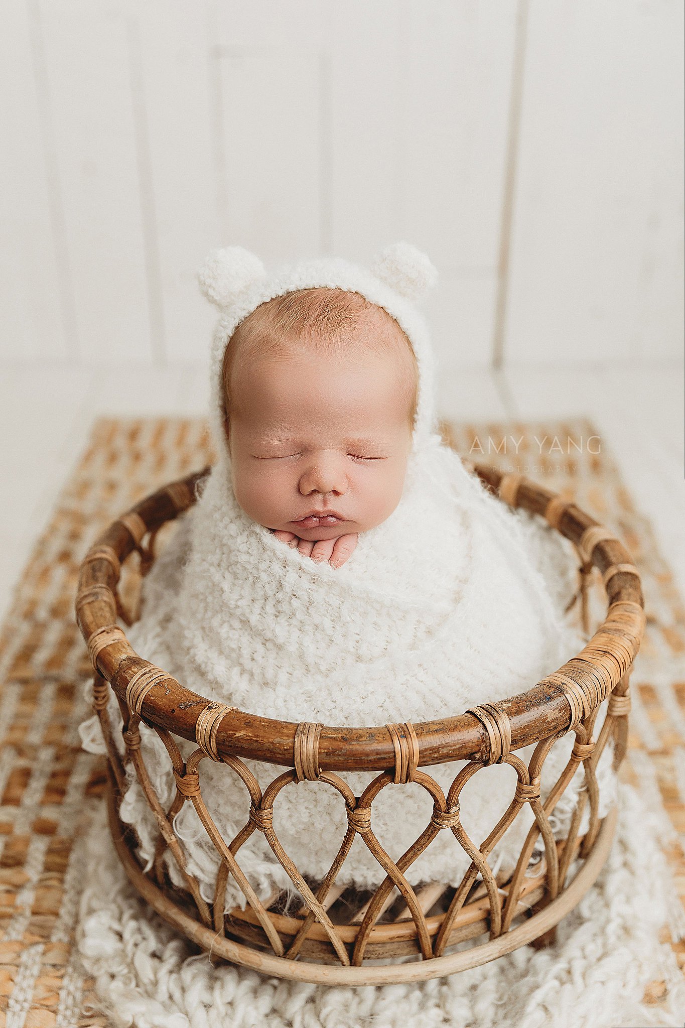 infant wrapped in white blanket and placed in basket by Charlottesville newborn photographer