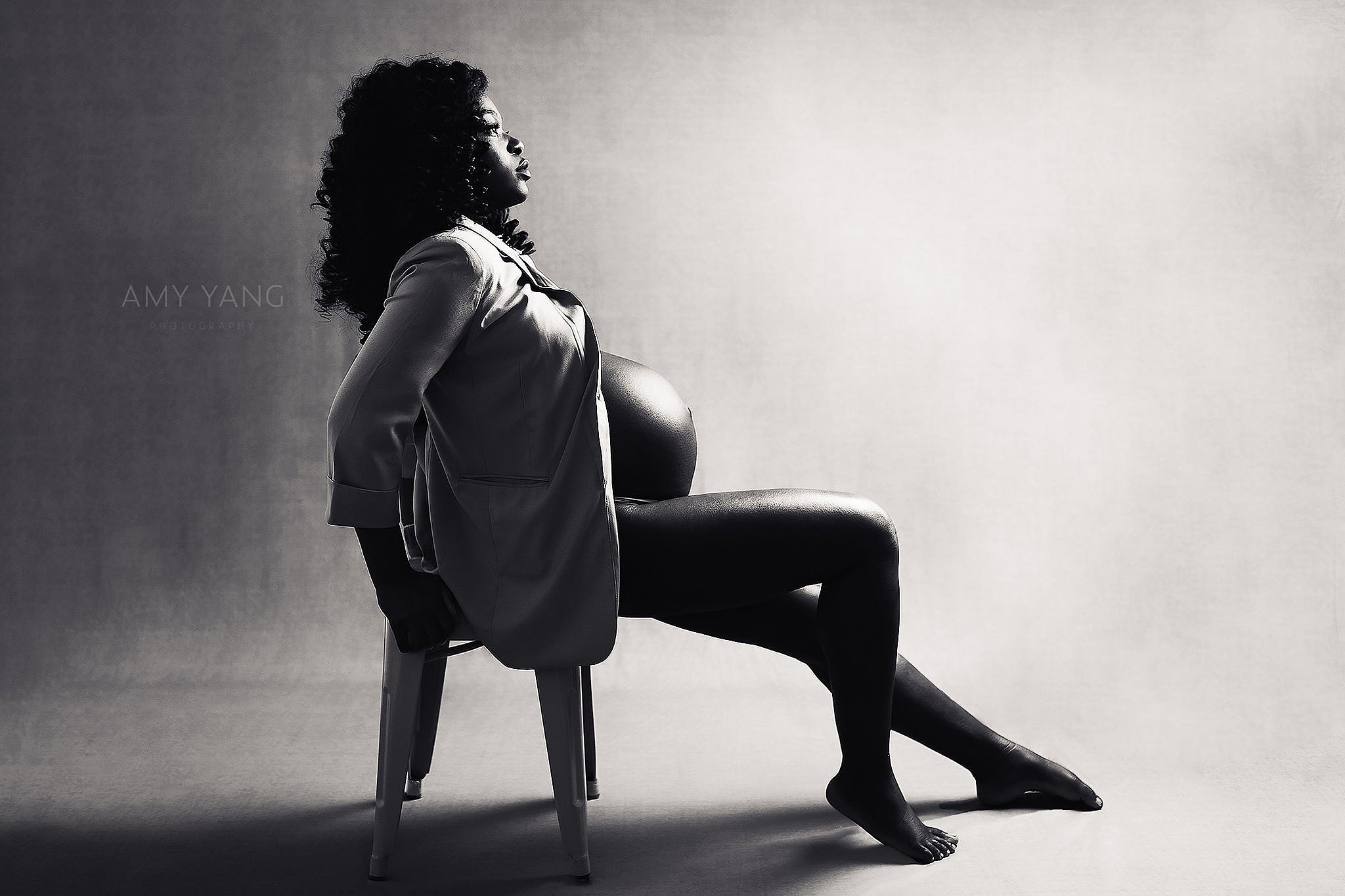 pregnant woman sits in chair with legs extended by Charlottesville photographer