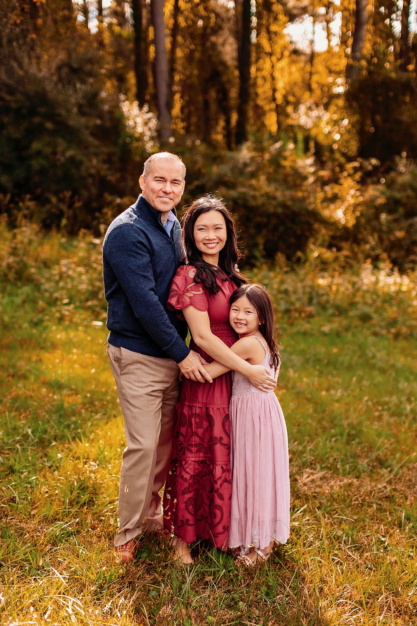 parents bug daughter in grassy area for park family session