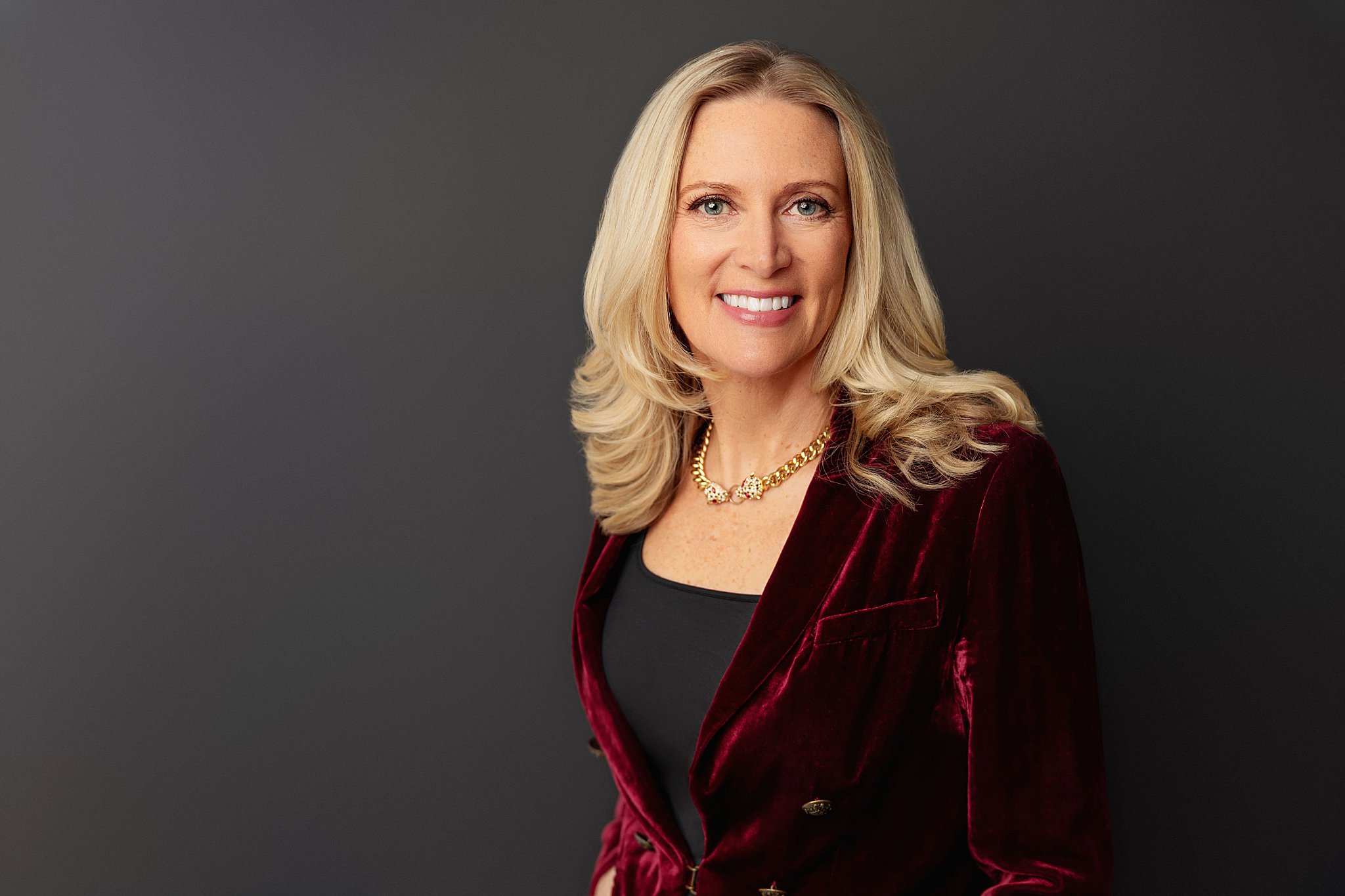 lady in red velvet blazer smiles for business portrait session