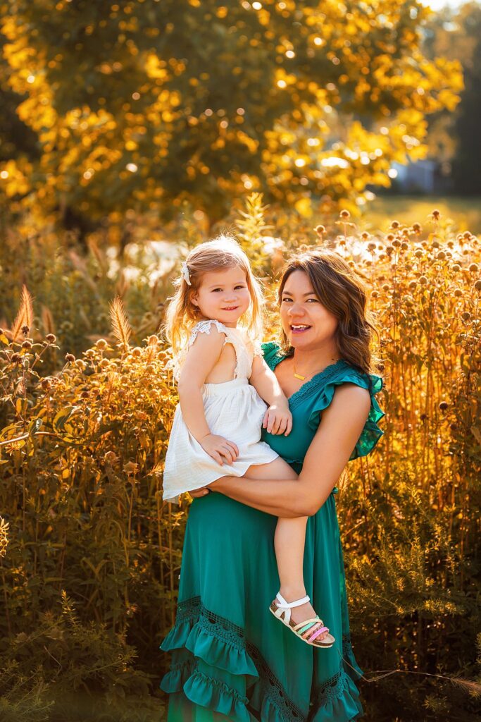 mother holds daughter at outdoor maternity session