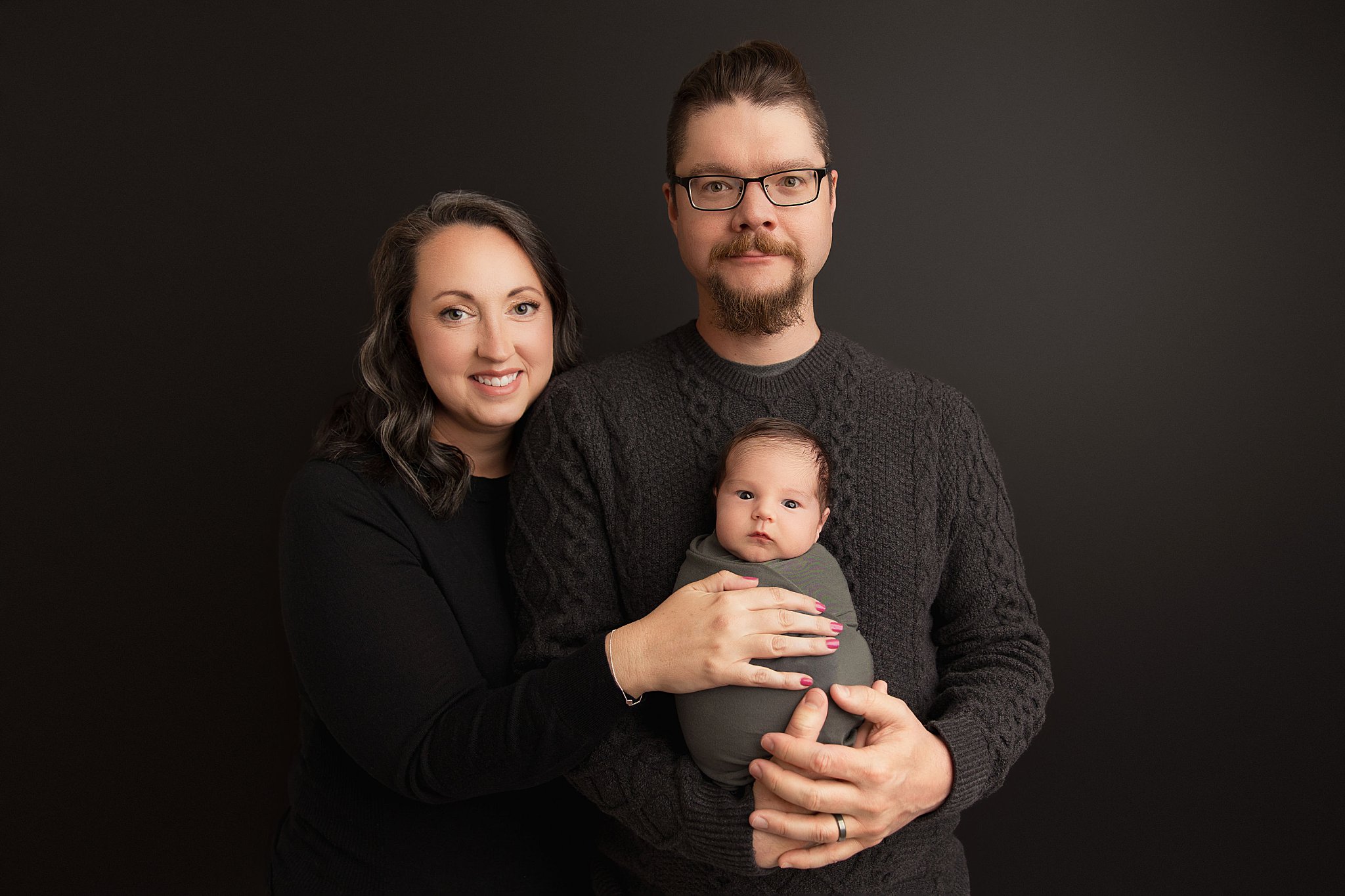 parents hold swaddled new baby by Amy Yang Photography