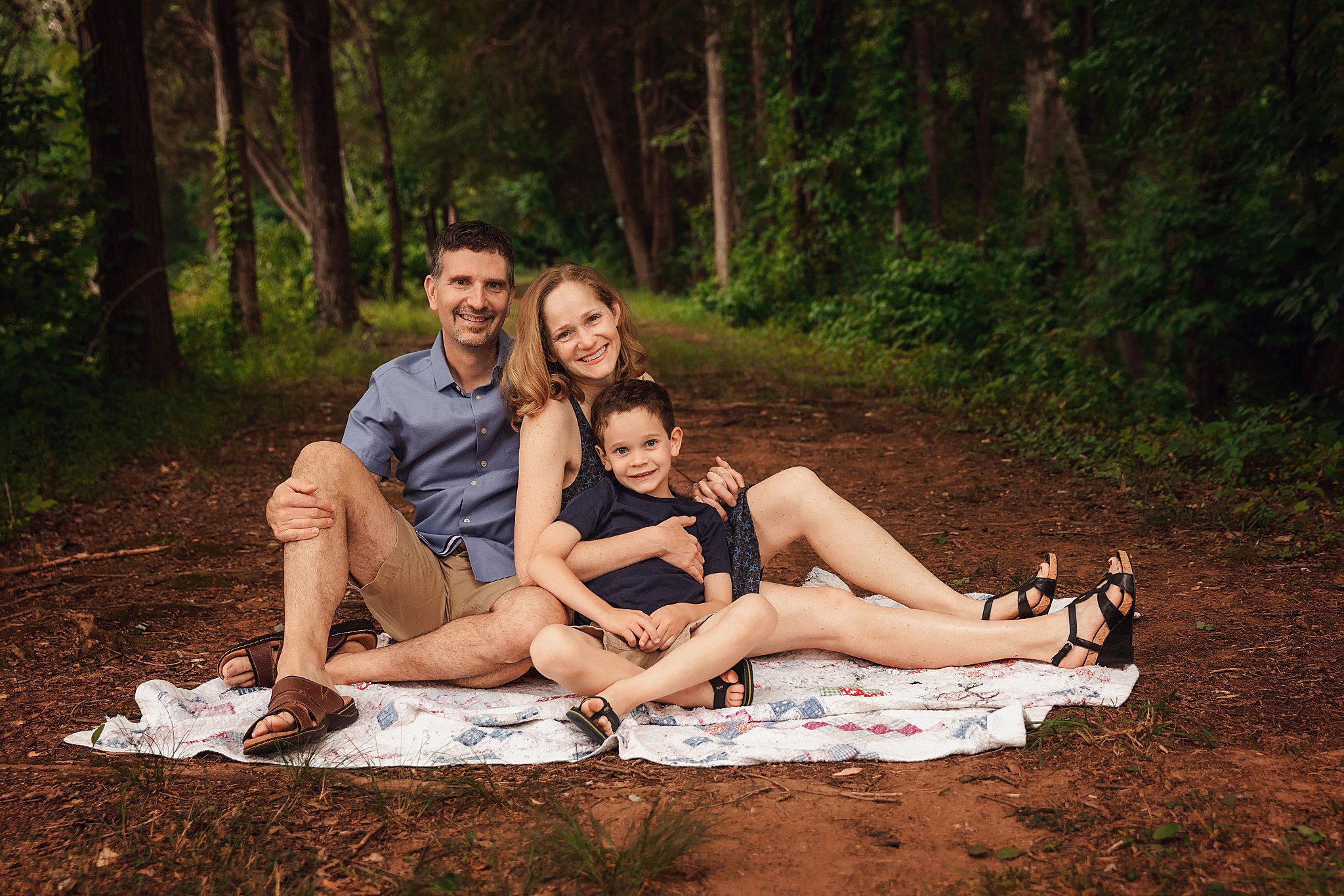 parents sit on blanket with son during simple family session 