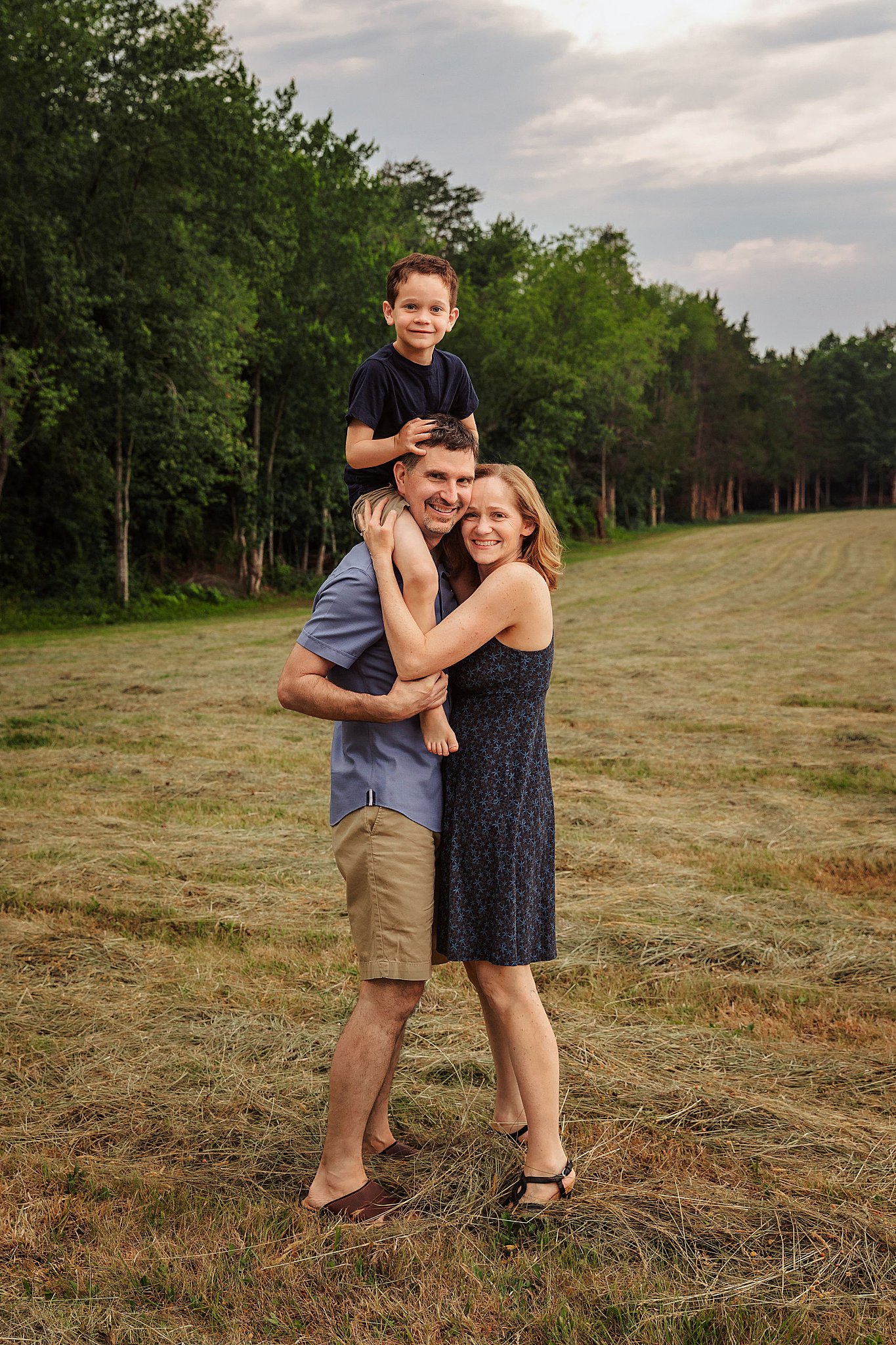 man carries son on his shoulders as mom hugs them by Charlottesville photographer