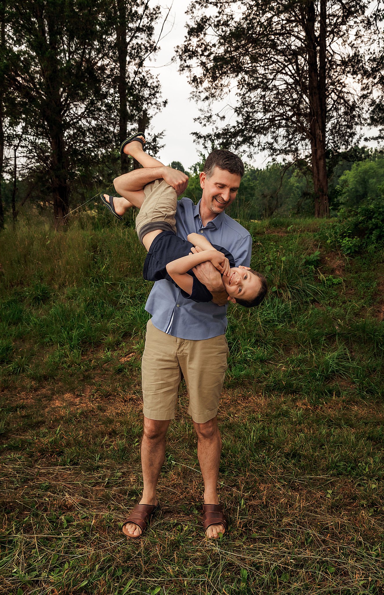 dad holds son upside down as boy smiles by Amy Yang Photography