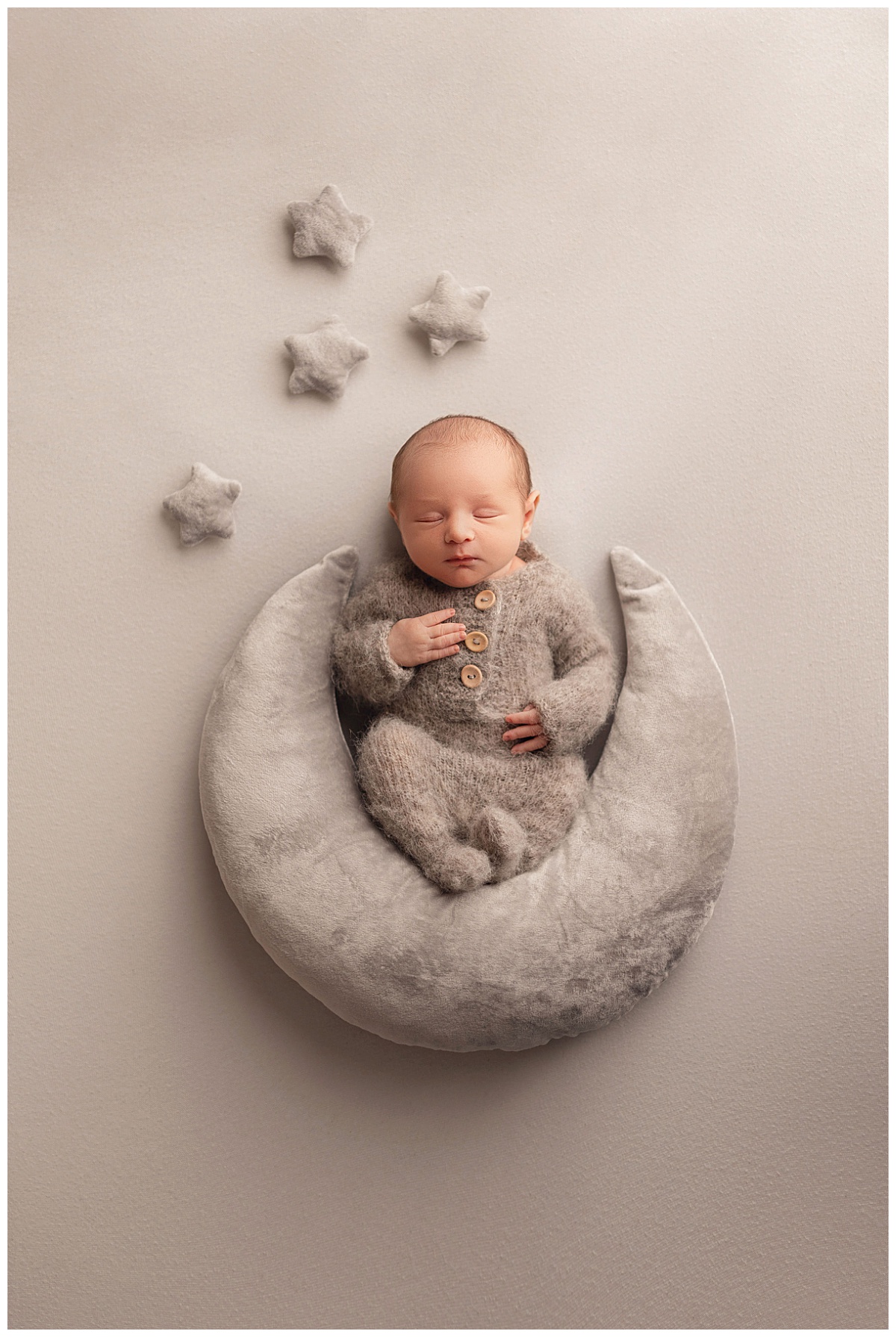 baby sits on stuffed moon surrounded by stars while he sleeps by Charlottesville Photographer