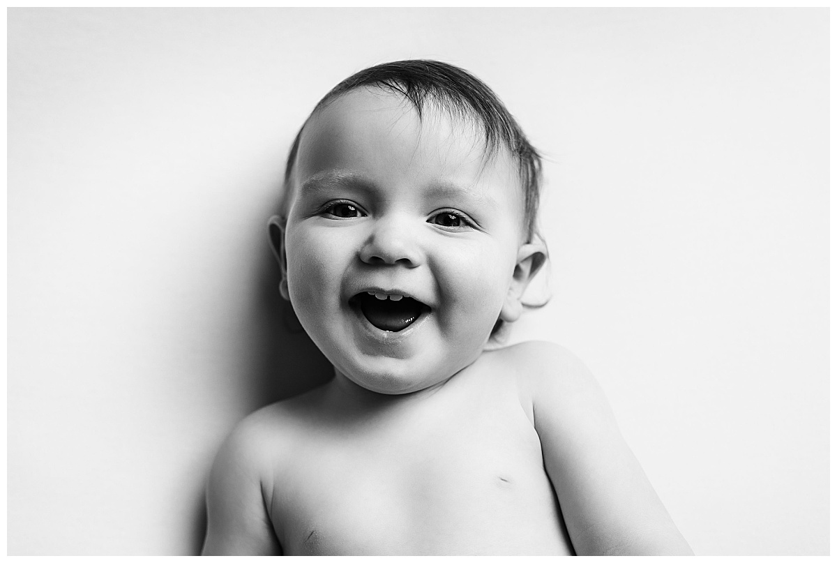 baby grins showing two front teeth during milestone studio session