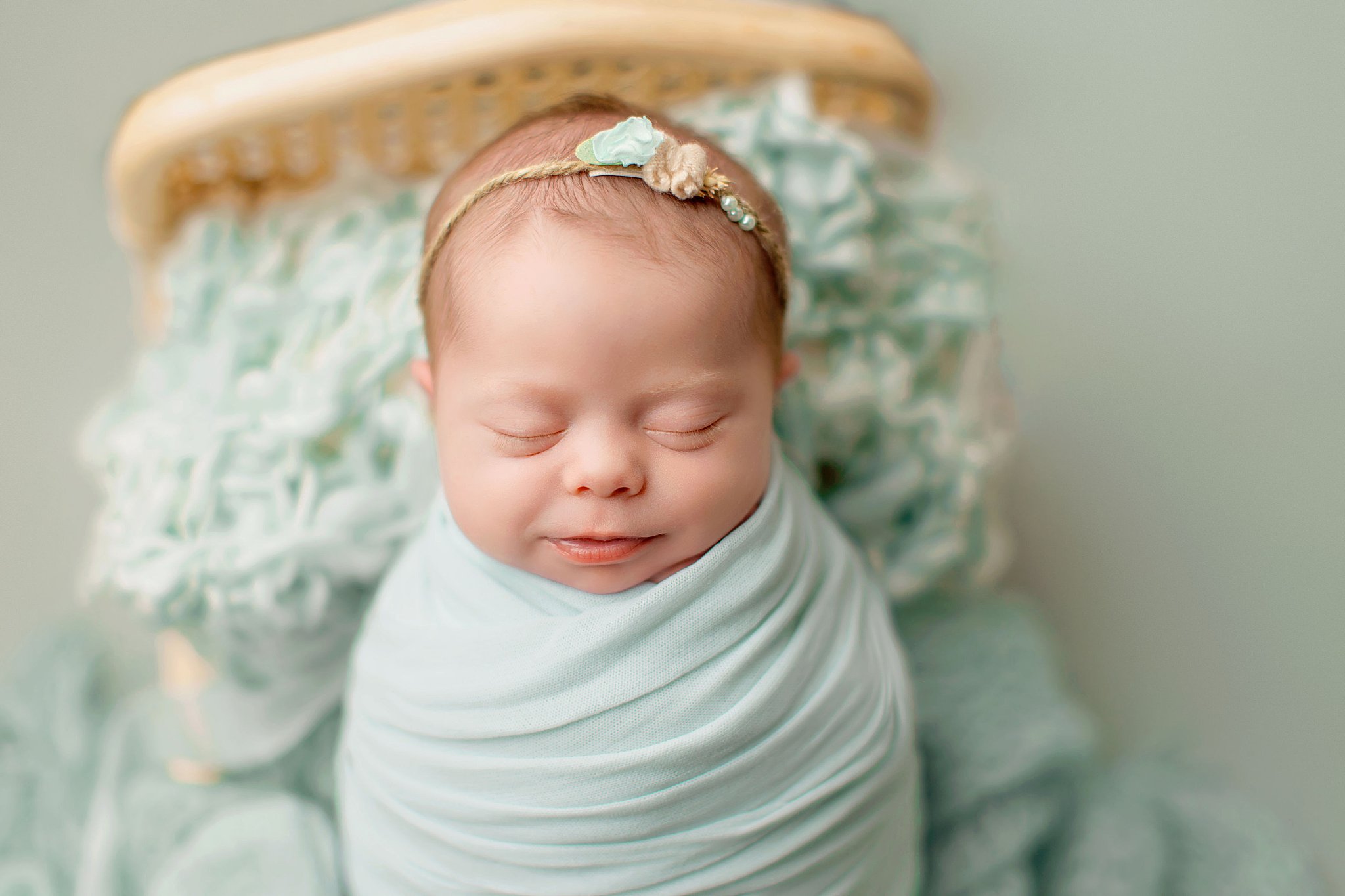 infant smiles as she sleeps in light blue swaddle by Charlottesville photographer