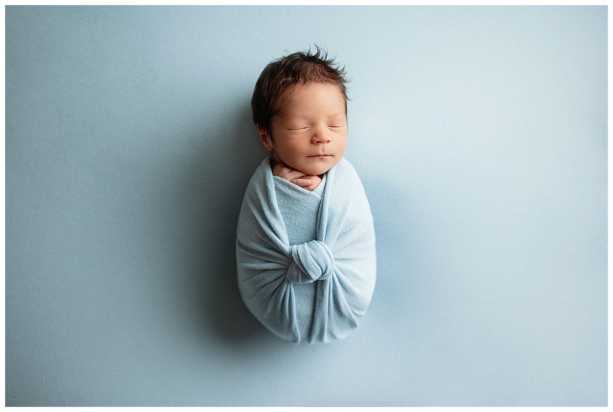 blue swaddle wraps baby during newborn session