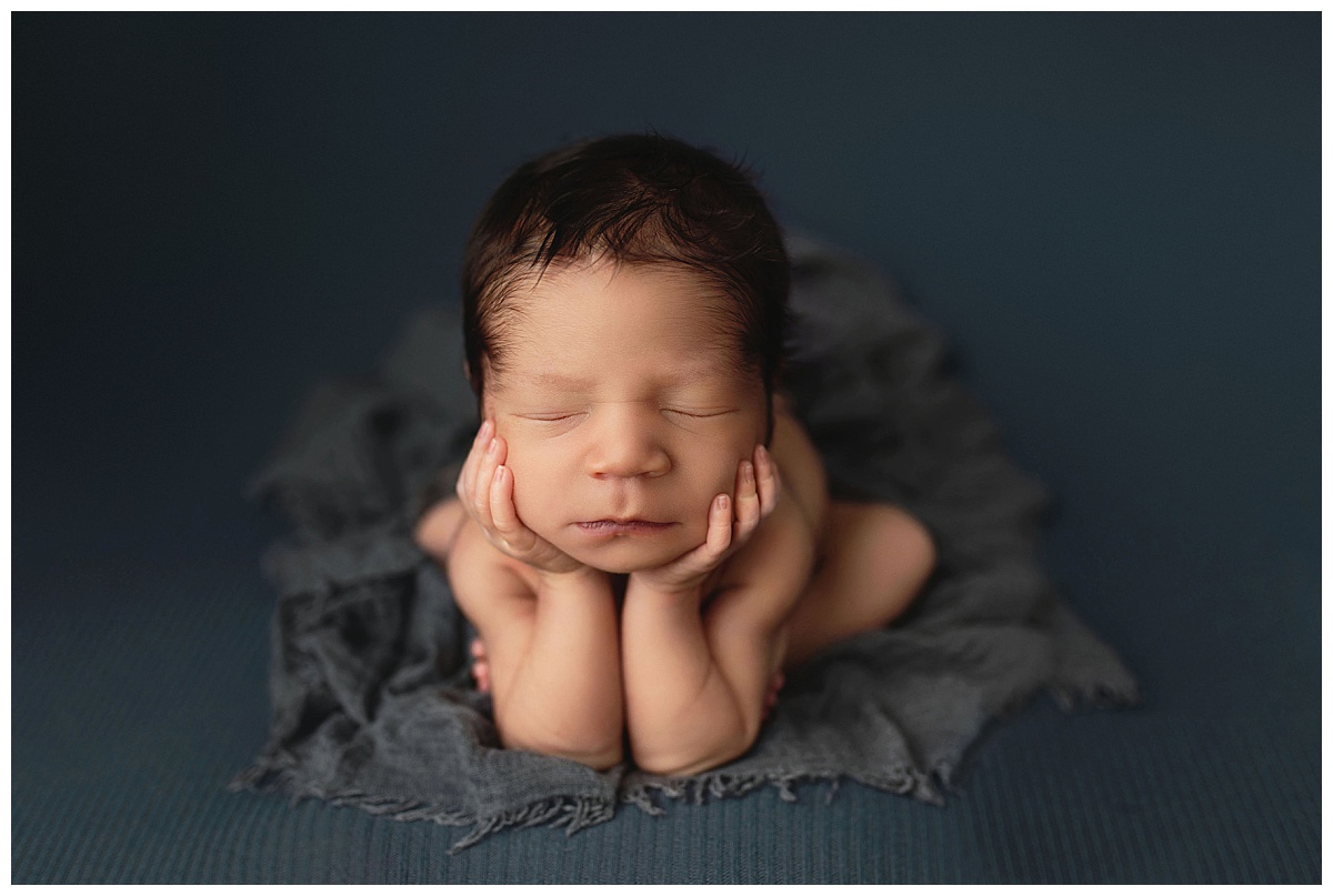 infant rests head in hands on a dark blue blanket by Amy Yang Photography