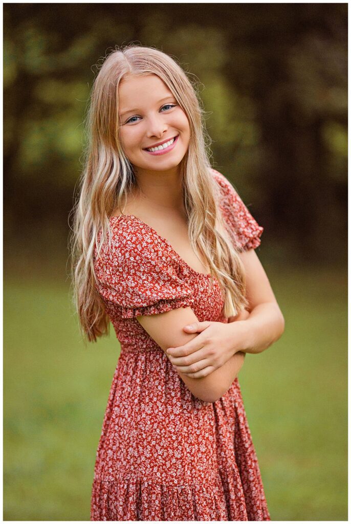 Smiling high school senior in a red floral dress during an outdoor portrait session with a senior photographer in Richmond, VA.