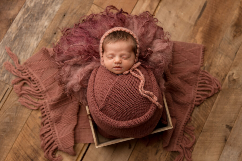 Wrapped newborn sleeping in a wooden crate during a newborn photography studio session with Amy Yang Photography in Charlottesville, VA.