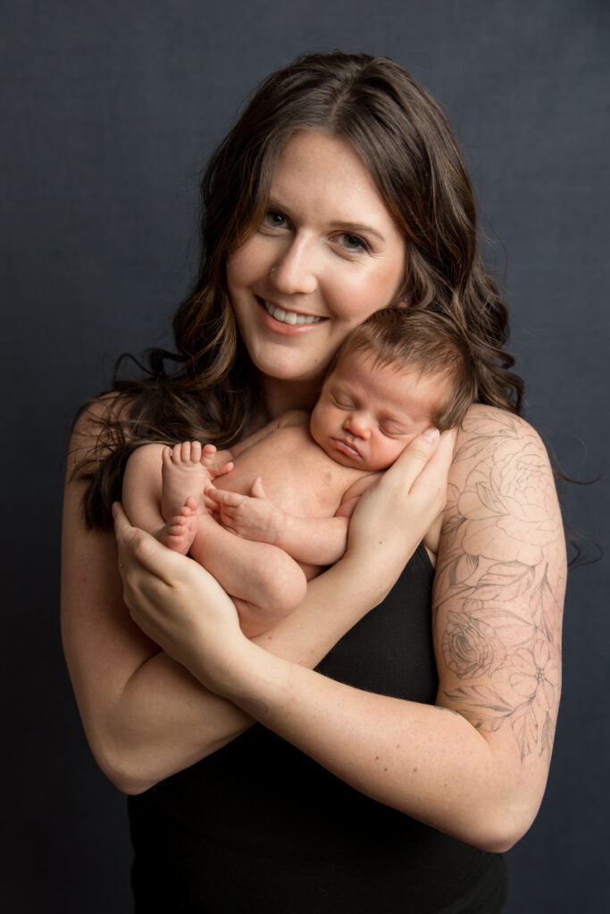 Mother holding her newborn during a professional newborn photography studio session.