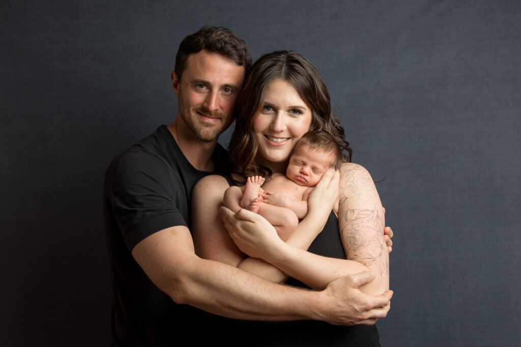 Parents cuddling their newborn during a professional newborn photography studio session in Charlottesville, VA.