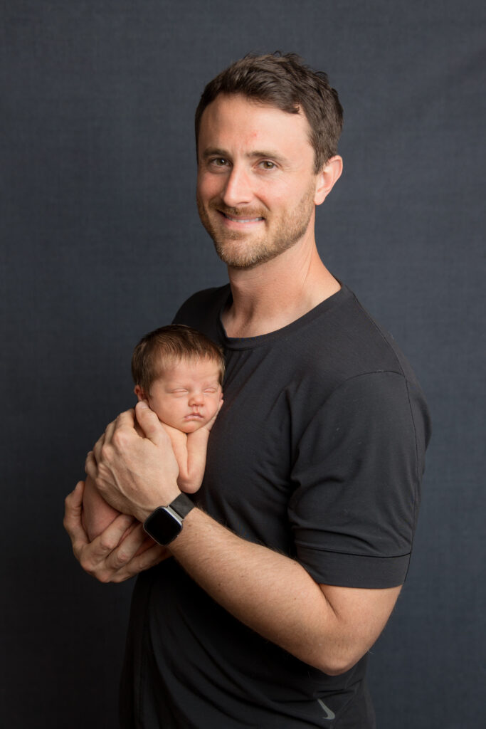 Father holding his sleeping newborn during a professional studio photography session with Amy Yang Photography.