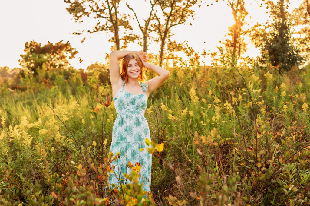 Full-length senior portrait of a high school senior posing in a wildflower meadow during golden hour with soft, glowing sunset light in Charlottesville, VA.