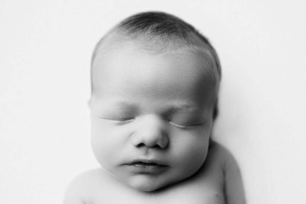 Peacefully sleeping baby in a timeless black-and-white heirloom newborn photography portrait.