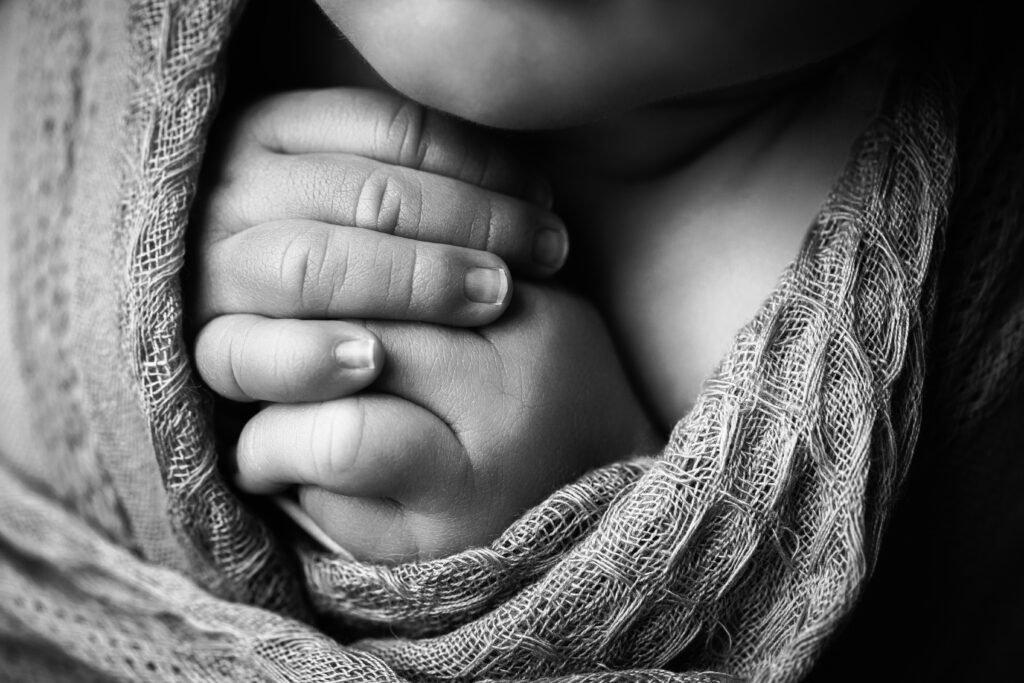 Tiny newborn fingers wrapped in soft fabric, showcasing the delicate details of heirloom newborn photography.