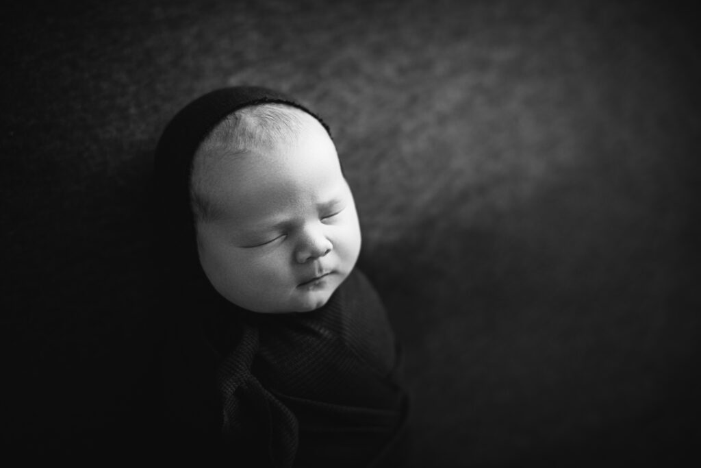 Elegant black and white luxury newborn photography portrait of a peacefully sleeping wrapped baby. Captured by Amy Yang Photography.