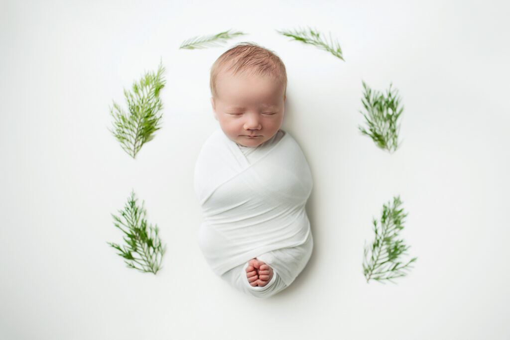Sleeping newborn wrapped on a white swaddle, during a newborn session with Amy Yang Photography at Charlottesville, VA.