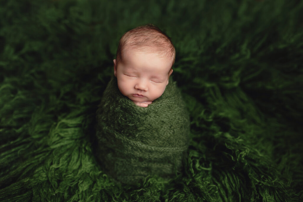 Wrapped newborn resting peacefully on a soft green blanket during a 2-4 hour newborn session in Charlottesville, VA.
