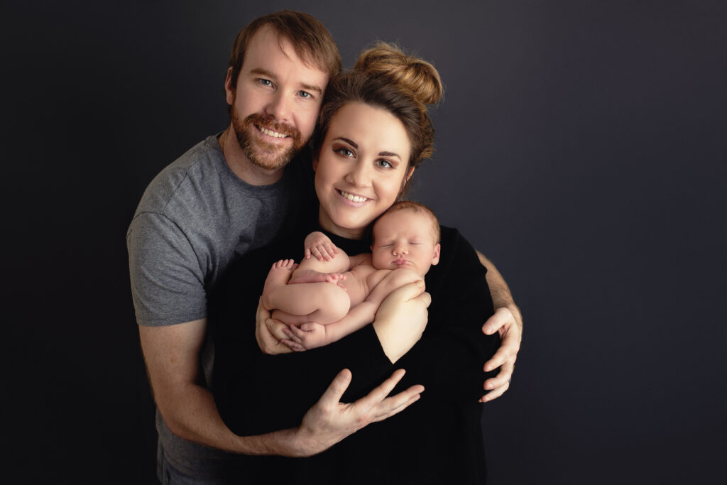 gently holding his sleeping newborn, illustrating what actually happens during a 2-4 hour newborn session with Amy Yang Photography.