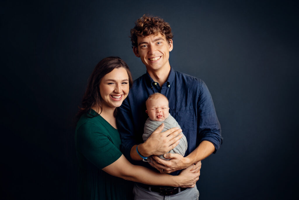 Happy parents holding their wrapped newborn during a timeless family portrait with a newborn photographer Crozet VA.