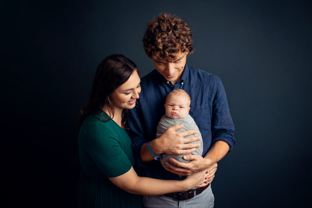 Newborn photographer Crozet VA creating a heartfelt family portrait as parents lovingly gaze at their baby.
