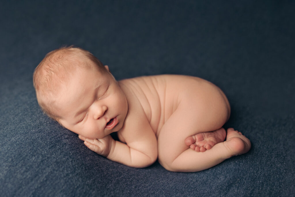 Sleeping newborn posed on a soft blue blanket by a newborn photographer in Ivy VA during a peaceful studio session.