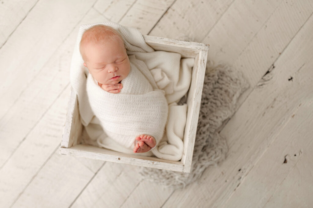 Wrapped newborn sleeping in a rustic wooden crate photographed by a newborn photographer in Ivy VA.