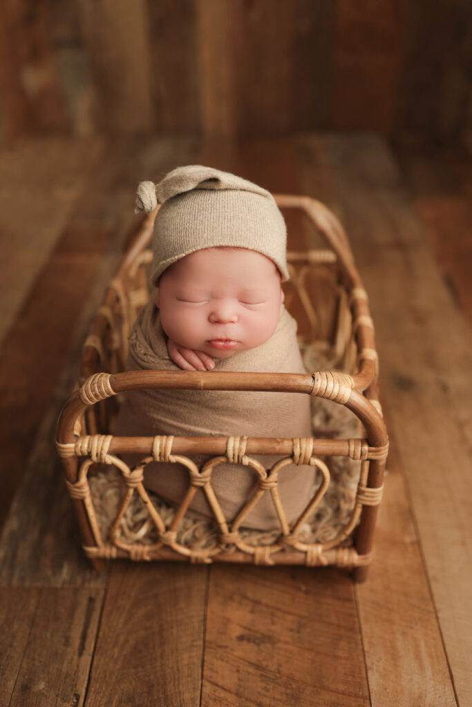Newborn photos as home decor featuring a sleeping baby in a woven bassinet with neutral tones.