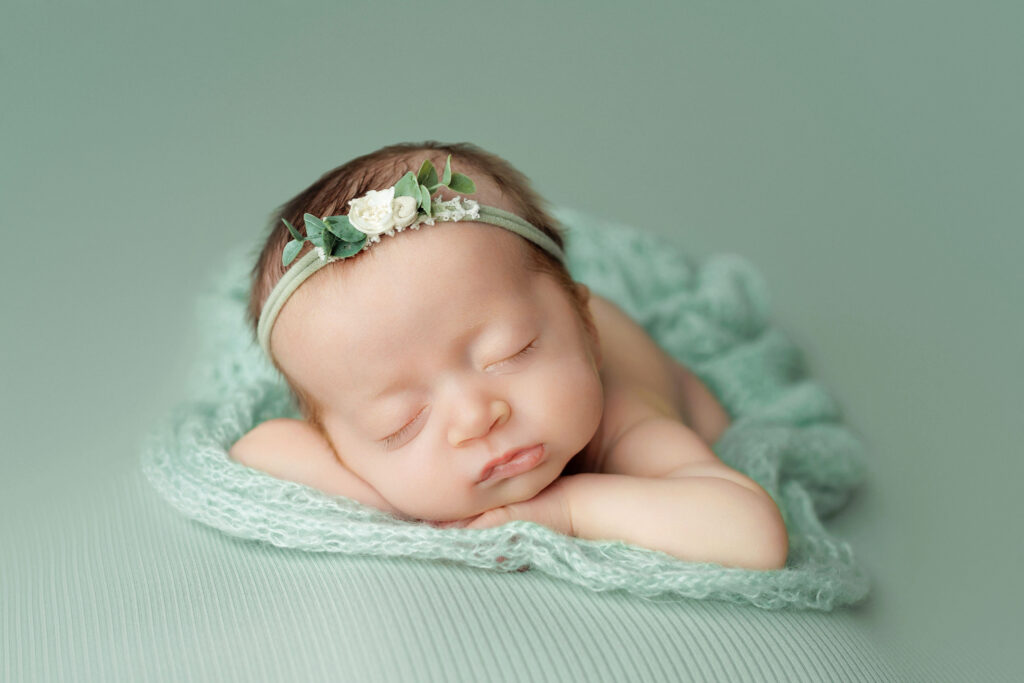 Sleeping newborn baby posed on a soft mint green blanket. Newborn photos captured in Charlottesville, VA.