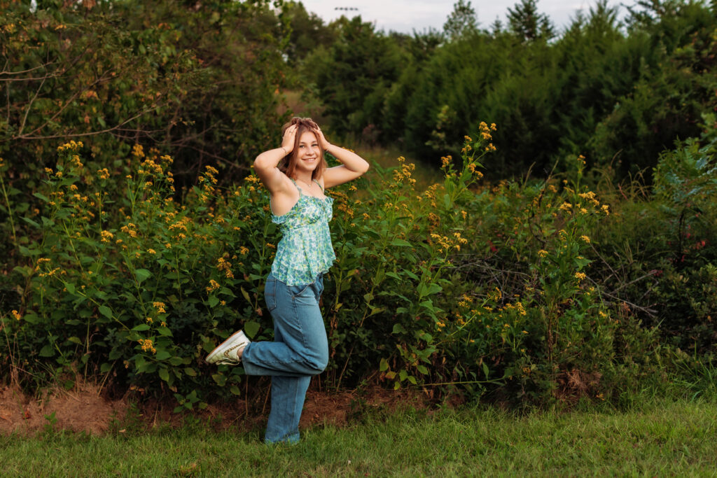 High school senior posing among wildflowers and evergreen trees during a multiple locations senior photos session with Amy Yang Photography.